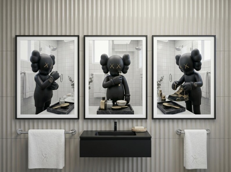 May include: A triptych of framed wall art prints featuring a matte black KAWS character in a bathroom setting. The left print shows the figure adjusting a watch, the centre shows it brushing teeth, and the right shows it holding a gold and black sneaker.