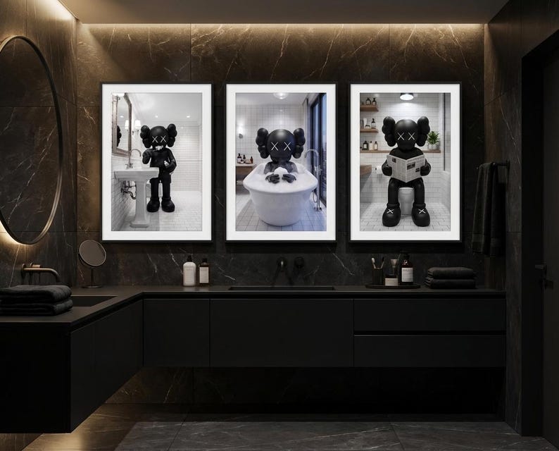 May include: Three framed black and white prints featuring a cartoon character in a bathroom setting. The character is depicted in various bathroom activities, including washing hands, bathing, and reading a newspaper. The prints are displayed above a black vanity in a modern bathroom.