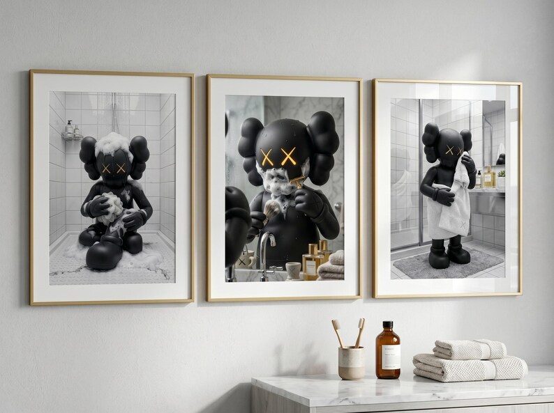 May include: A set of three framed wall art prints featuring a black KAWS-style character in a bathroom setting. The first print shows the character bathing, the second shows it shaving, and the third shows it drying off with a white towel.