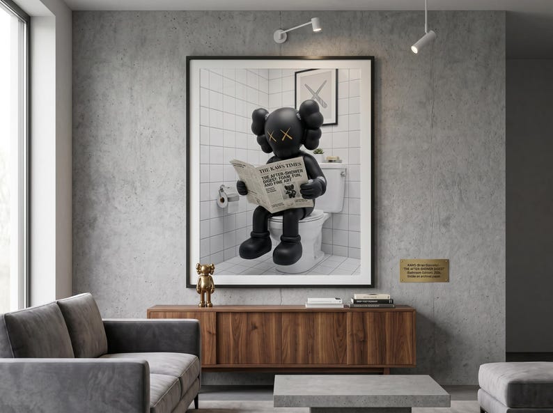 May include: A framed wall art print featuring a black cartoon character with X-shaped eyes sitting on a white toilet and reading a newspaper titled The Kaws Times. A small gold figurine stands on a wooden cabinet below the framed artwork.