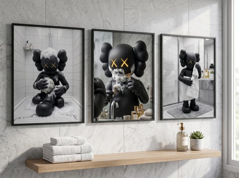 May include: A set of three framed wall art prints featuring a black cartoon character with X-shaped eyes in a bathroom setting. The prints show the character bathing, shaving, and drying off with a white towel, all rendered in a monochromatic style.