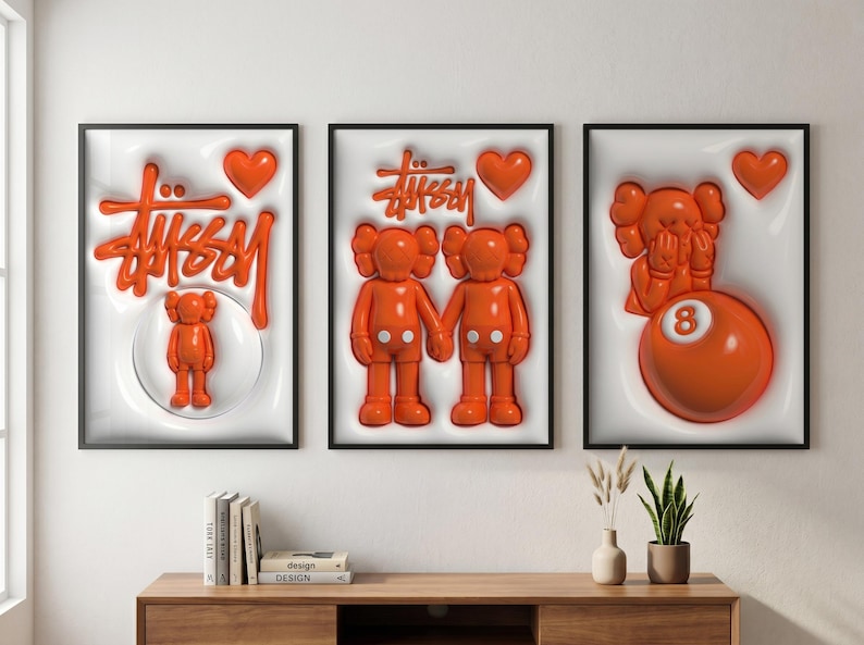 May include: Three framed art prints featuring orange pop art designs. One print displays the Stussy logo and a small figure, another shows two figures holding hands, and the third has a figure and an orange 8-ball.