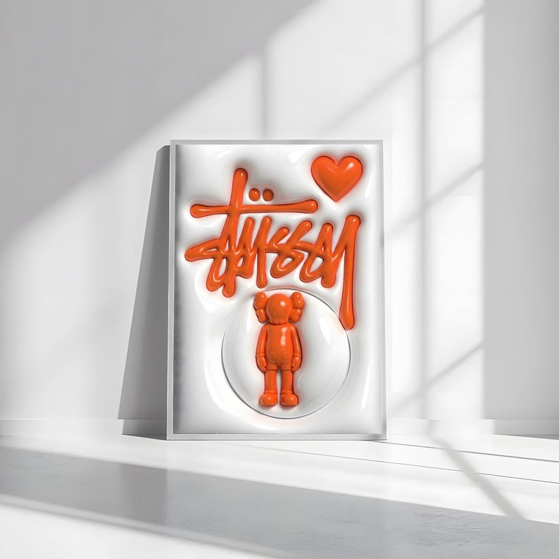 May include: Orange artwork featuring the Stussy logo, a heart, and a KAWS-style figure. The design is raised against a white background, framed in a white border. The artwork is displayed on a white surface with shadows.