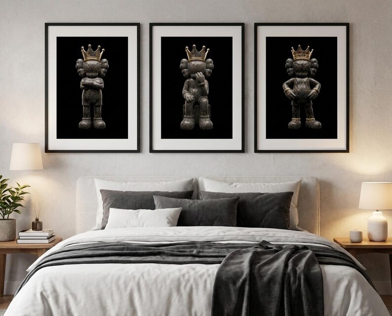 Pu&ograve; includere: Tre stampe artistiche incorniciate con una figura grigio scuro con una corona d'oro su sfondo nero. La figura &egrave; in diverse pose in ogni stampa. Le stampe sono esposte sopra un letto con lenzuola bianche e cuscini grigi.