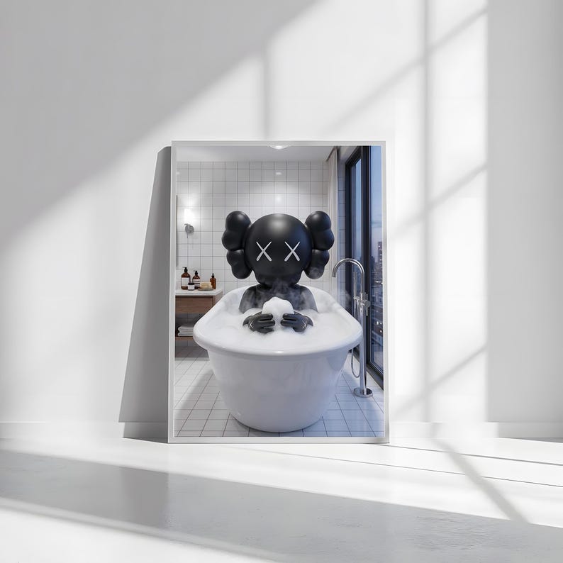May include: A framed print featuring a black figure with crossed-out eyes and a round head, relaxing in a white bathtub filled with bubbles. The figure is holding a white object. The bathroom setting includes a window and tiled walls.