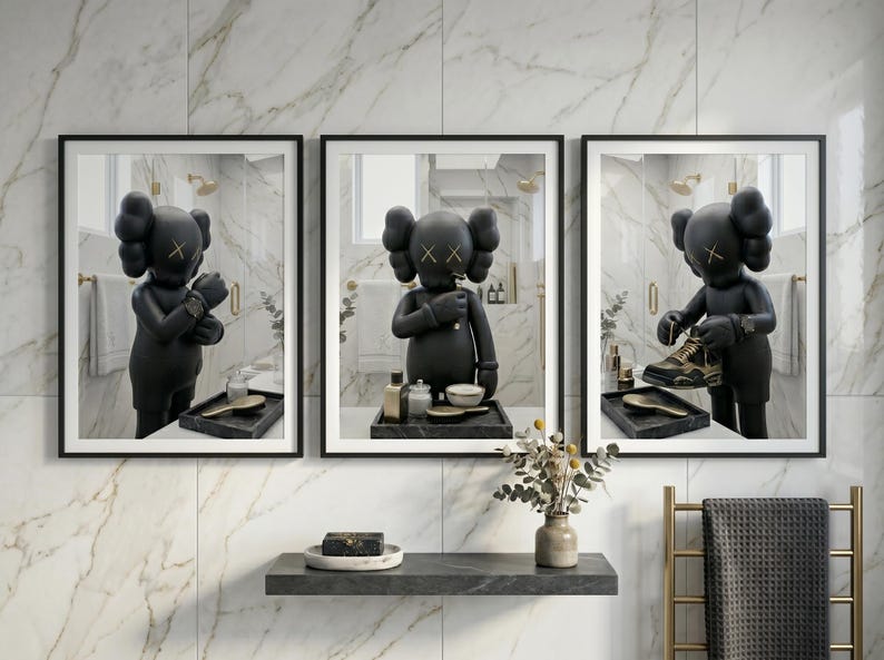 May include: A set of three framed wall art prints featuring a black KAWS character in a bathroom setting. The left print shows the figure adjusting a watch, the centre shows it grooming, and the right shows it holding a sneaker, all in black frames.
