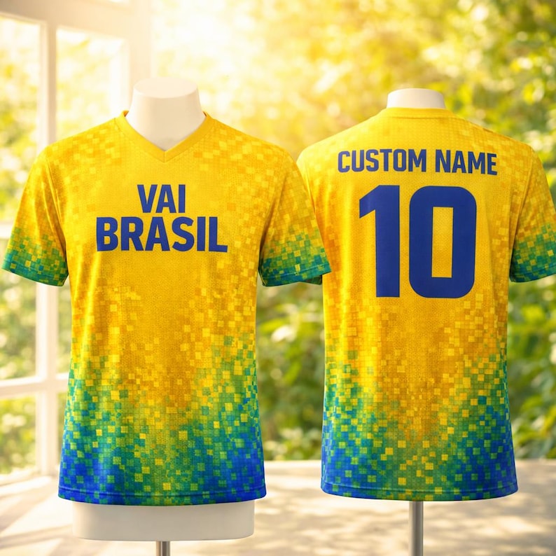 Puede incluir: Una camiseta de f&uacute;tbol amarilla con un dise&ntilde;o pixelado. La parte delantera muestra el texto "VAI BRASIL" en azul. La parte trasera muestra "CUSTOM NAME" encima del n&uacute;mero "10" en azul. La camiseta tiene cuello en V y un degradado verde y azul en las mangas y el dobladillo.