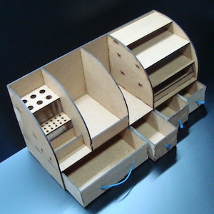May include: A wooden desk organizer with multiple compartments, shelves, and drawers. The organizer has a natural wood finish and includes a section for pens and pencils. The drawers have blue pull strings.