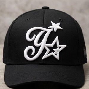 May include: Black baseball cap with a white embroidered design of the letter "F" and two stars. The cap has a curved peak and a structured fit. The New Era logo is visible on the side.