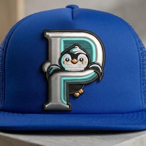 May include: A blue trucker hat with a white and teal embroidered letter "P" featuring a cartoon penguin. The hat has a mesh back and a curved brim. The penguin has a cute expression.