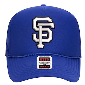 Peut inclure: Casquette de camionneur bleu roi avec un logo blanc et noir. Le chapeau présente un dos en filet et une visière incurvée. L'avant du chapeau affiche les lettres "SF" dans un design stylisé. Fermeture à pression.