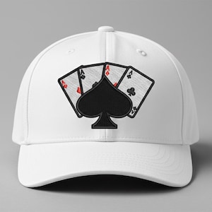 May include: White baseball cap featuring an embroidered design of playing cards. The design includes three Aces and a black spade symbol. The Aces have red and black details. The cap is set against a gray background.