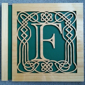May include: A wooden plaque featuring a Celtic knot design surrounding the letter "F" on a green background.