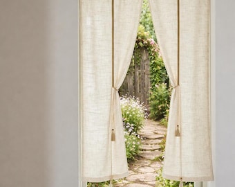 May include: Beige linen curtains framing a view of a garden path. The curtains are tied back with rope, revealing a stone path, wooden fence, and lush greenery. The curtains have a simple, natural design.