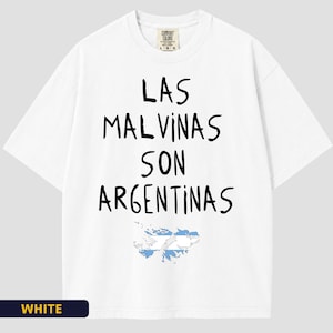 May include: A white short-sleeved t-shirt featuring the black text 'LAS MALVINAS SON ARGENTINAS' printed on the chest. Below the text is a graphic of the Malvinas Islands filled with the light blue and white colours of the Argentine national flag.