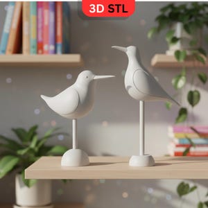 May include: Two white bird sculptures on a wooden shelf. The birds have long beaks and are mounted on thin, white stands with circular bases. The text "3D STL" is in a red rectangle in the top center of the image. Books and plants are in the background.