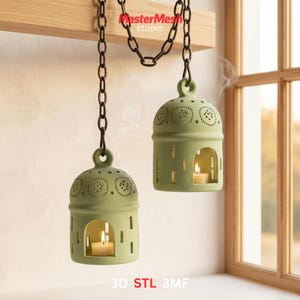 May include: Two hanging, sage green candle lanterns with a domed top and cut-out designs. Each lantern has a small, lit candle inside, emitting a soft glow. The lanterns are suspended by a dark chain from a wooden beam. The text "MasterMesh STUDIO" and "3D STL 3MF" are visible.