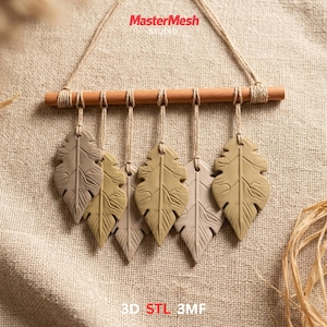 May include: A wall hanging with six leaf-shaped ornaments in beige and olive green. The leaves are suspended from a wooden dowel with twine. The text "MasterMesh Studio" and "3D STL 3MF" are visible. A rustic home decor item.