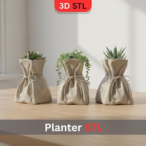 May include: Three beige fabric planters, each filled with different green plants. The planters are tied with a string at the top. The text "3D STL" is at the top and "Planter STL" is at the bottom.