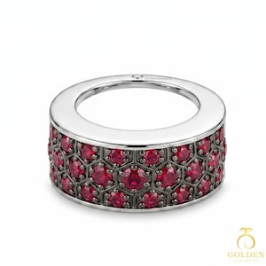 May include: A wide, silver ring with a band of red gemstones set in a honeycomb pattern. The gemstones are a vibrant red color, and the ring has a polished finish. The ring is a piece of jewelry.