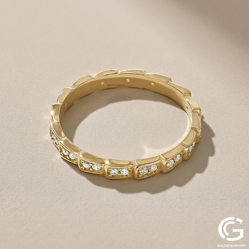 "A direct top-down view of the 14k gold and diamond geometric eternity ring. The circular shape is clear, and the pave diamonds are visible on the exterior segments. Small brand engravings are present on the inner band."