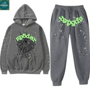 Könnte beinhalten: Graues Hoodie- und Jogginghosen-Set. Der Hoodie zeigt das Wort "sp5der" in Neongrün, eine Spinnennetz-Grafik und Sternakzente. Die Jogginghose hat ebenfalls das Wort "sp5der" in Neongrün und Sternakzente.