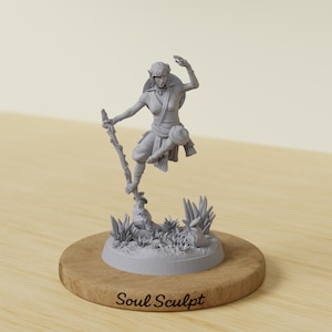May include: A gray resin miniature figurine of an elf-like character in a dynamic pose, holding a gnarled staff while standing on a rocky base with foliage. The round wooden display base features the engraved text Soul Sculpt in black script.