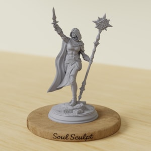 May include: A gray figurine of a robed figure holding a sword and a staff with a star-shaped top. The figurine is on a wooden base with the text "Soul Sculpt". The figure is standing on a rocky base.
