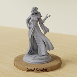 May include: A grey figurine of a woman in a flowing gown, cape, and intricate bodice, standing on a circular base. The base is set on a wooden stand. The text "Soul Sculpt" is visible on the base.