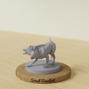 Könnte beinhalten: Graue, dreiköpfige Hundefigur, möglicherweise Zerberus, steht auf einem grauen Sockel auf einer Holzscheibe. Die Figur ist detailliert mit Fell und Muskeldefinition. Der Text "Soul Sculpt" ist auf der Holzbasis aufgedruckt.