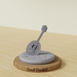 May include: A grey miniature mandolin sculpture on a round, grey platform, set on a wooden base. The mandolin has intricate details and is angled slightly. The base has the text "Soul Sculpt".