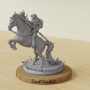 Puede incluir: Escultura gris de una figura montada en un caballo encabritado, con una capa fluida y un arma. La escultura está montada sobre una base de madera con el texto "Soul Sculpt". El caballo está rodeado por un diseño en forma de llama.