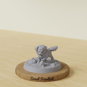 May include: A light gray miniature figurine of a small, fluffy dog standing on a circular base. The dog has one paw resting on a human skull. The base is mounted on a round wooden plaque with the text Soul Sculpt engraved on the front surface.