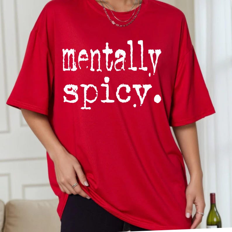 May include: A red t-shirt with the white text "mentally spicy." The shirt has short sleeves and a relaxed fit. The text is in a bold, slightly distressed font.