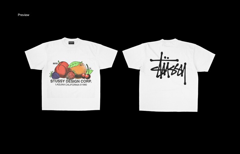 May include: White t-shirts with a fruit graphic and the Stussy Design Corp. logo. One shirt features a colorful illustration of peaches, berries, and cherries. The other shirt displays the Stussy logo in black.