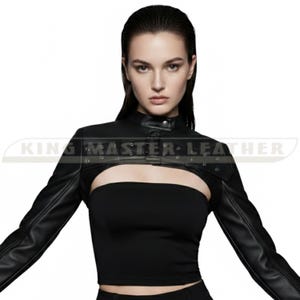 May include: Black leather bolero jacket with long sleeves and a high collar. The jacket has a cutout design across the chest and is fastened with a single button. The text "KING MASTER LEATHER" is printed on the jacket.