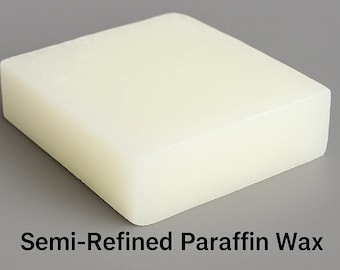 May include: A rectangular block of semi-refined paraffin wax, off-white in color, sits on a gray surface. The text "Semi-Refined Paraffin Wax" is displayed in black at the bottom of the image.