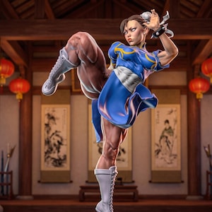Puede incluir: Una figura coleccionable detallada de un artista marcial en pose de patada alta. La figura viste un qipao azul con ribetes amarillos, una faja blanca y botas blancas con cordones. Presenta muñequeras negras con pinchos y peinado con dos moños.