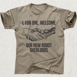 May include: Tan t-shirt with the text "I, FOR ONE, WELCOME OUR NEW ROBOT OVERLORDS" above an illustration of a human hand shaking a robotic hand. The design is in black.