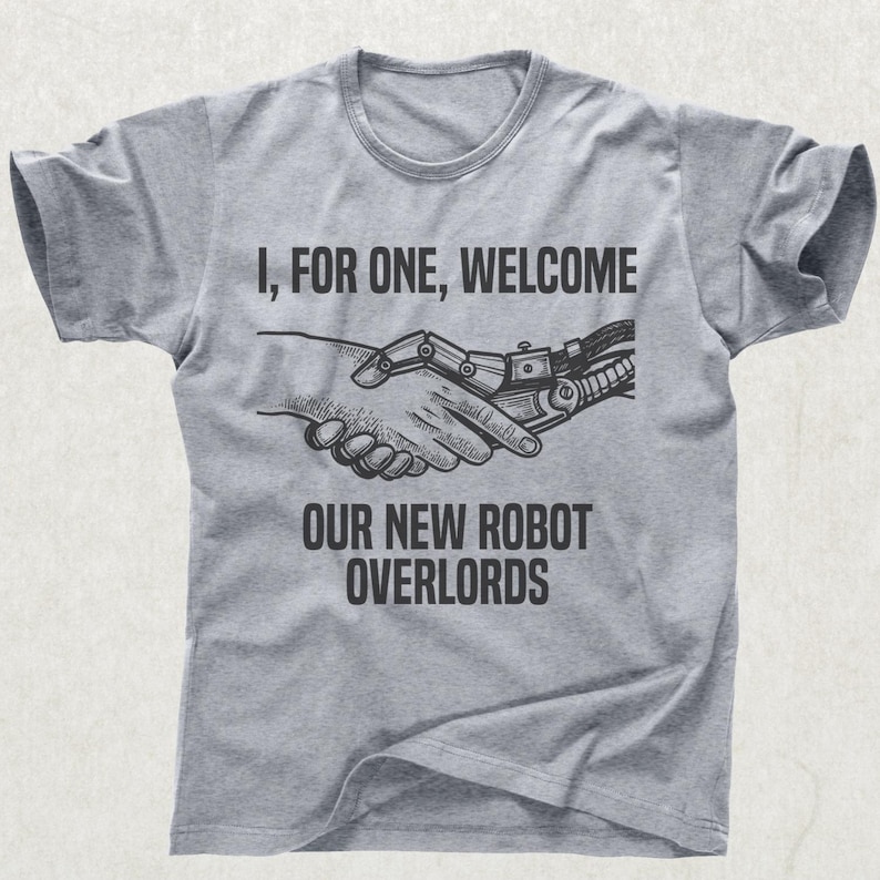 May include: A gray t-shirt with a crew neck featuring the text "I, FOR ONE, WELCOME OUR NEW ROBOT OVERLORDS." The graphic shows a human hand shaking hands with a robotic hand.