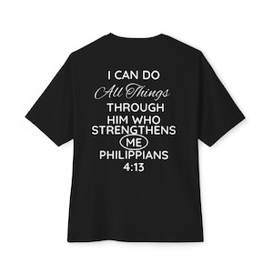 May include: A black short-sleeved t-shirt featuring white text on the back that reads: I CAN DO All Things THROUGH HIM WHO STRENGTHENS ME in an oval, PHILIPPIANS 4:13. The design uses a mix of bold sans-serif and elegant script fonts.