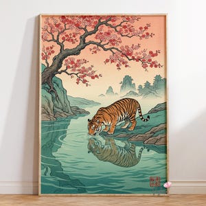 May include: A framed art print depicting a tiger drinking from a river, with a reflection in the water. The scene is set in a landscape with a cherry blossom tree, mountains, and a traditional Japanese building. The color palette includes orange, green, and pink.