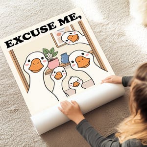 May include: A rolled-up poster featuring a cartoon illustration of a family of geese. The geese have white feathers, orange beaks, and pink cheeks. The poster has the text "EXCUSE ME," in black letters at the top.