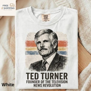 May include: White t-shirt featuring a portrait of Ted Turner with a retro striped background in orange, yellow, and blue. The text reads "TED TURNER FOUNDER OF THE TELEVISION NEWS REVOLUTION". The shirt has a crew neck and a Comfort Colors tag.
