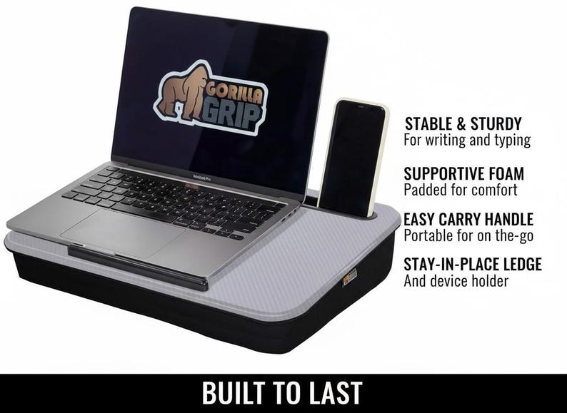 Op de afbeelding: Een zwart en grijs laptopbureau met een laptop en een smartphone. De laptop heeft een "Gorilla Grip" logo. Tekst aan de zijkant luidt "Stable & Sturdy", "Supportive Foam", "Easy Carry Handle" en "Stay-in-Place Ledge". De woorden "Built to Last" staan onderaan.