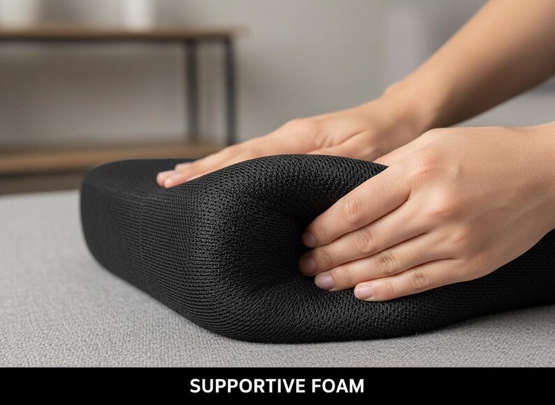 Op de afbeelding: Een zwart, ondersteunend schuimkussen wordt samengedrukt door twee handen. Het kussen heeft een mesh-achtige textuur. De tekst "SUPPORTIVE FOAM" wordt onderaan de afbeelding weergegeven.