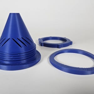 May include: A blue plastic cone-shaped component featuring diagonal ventilation slits near the base, accompanied by a matching circular threaded locking ring and a separate flat, thin blue ring with a textured outer edge.