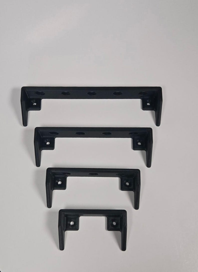 Pu&ograve; includere: Un set di quattro reggimensola in metallo nero opaco disposti in formazione nidificata dal pi&ugrave; grande al pi&ugrave; piccolo. Ogni supporto presenta un design a forma di U con fori per le viti preforati lungo la piastra posteriore e due bracci.