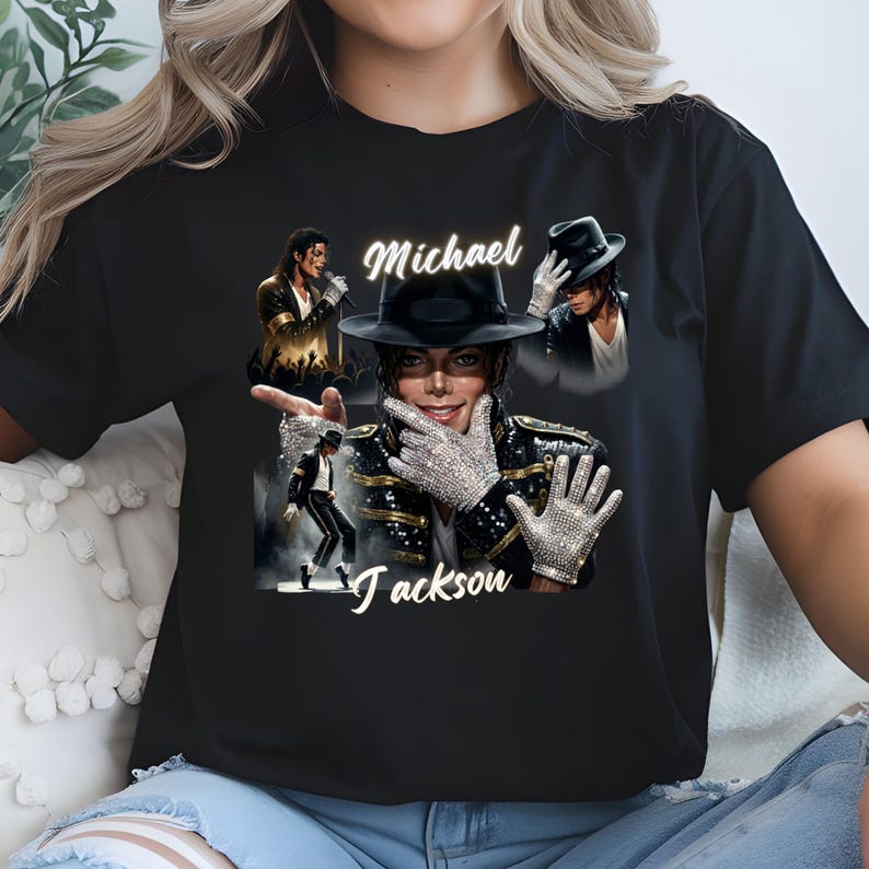 May include: Black t-shirt featuring multiple images of Michael Jackson, including a portrait with a black hat and sparkling gloves. The name "Michael Jackson" is written in a stylized font across the shirt. The shirt is a classic crew neck.