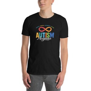 Puede incluir: Camiseta negra con las palabras "AUTISM Acceptance" en texto colorido y un símbolo de infinito. La camiseta también tiene las palabras "ADVOCATE • EDUCATE • ACCOMMODATE • INCLUDE" encima del símbolo de infinito.